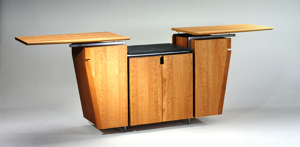<p>Dining Cabinet</p><p>1995</p><p>Designed as a multi-purpose Dining room cabinet for a residence in West Vancouver. The top slides open allow for more surface area to place hot foods on the granite top.</p><p>Cherry veneer plywood, with aluminum roll-top fronts,and wheels.</p><p>Height 38'' Depth 23'' Length 76'' Extended 108''</p>